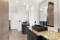 The primary bathroom offers dual stone sinks, granite counters, custom cabinetry, custom mirrors and plenty of storage.