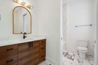 Gorgeous walnut cabinetry in the secondary bath pops beautifully against the white quartz of the vanity