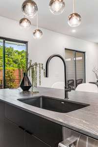 Black porcelain sink pairs beautifully with the Dekton counters and single arch black faucet