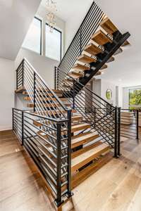 Floating staircase with fabulous custom treads were manufactured by the flooring company to perfectly match the hardwood floors. Note the gorgeous custom iron hand rails.