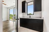 Italian matte black cabinets extend into the laundry room which has a sink and ample built-ins