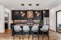 Another view of this gorgeous kitchen showing the continuous Dekton backsplash highlighted beautifully by the under-cabinet lighting. Warm slat wood panels on the range hood and soft gold lighting bring warmth and light to the space.