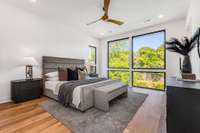 Primary bedroom with amazing light from the floor-to-ceiling windows and no homes in back