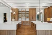 The dining room flows into the spacious kitchen with it's double islands and abundant cabinet storage, with the bar and wine room located on the left.