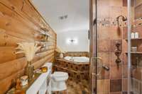 Primary bath features updated lighting, renovated shower, glamorous gold accents, and a soaking tub