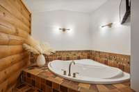 Primary bath features updated lighting, renovated shower, glamorous gold accents, and a soaking tub