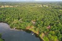 Aerial view showcases the 5 lush acres surrounding your waterfront home and dock, offering peace and privacy