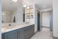 Primary bath features double vanity, marble counters,  built-in shelving, linen closet, walk-in closet, and private water closet