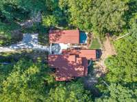 An aerial view reveals the stunning scale of this Spanish colonial retreat, surrounded by five serene wooded acres. It’s a perfect blend of privacy and proximity to local amenities.