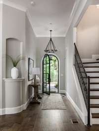 Step into a spacious, sunlit entryway that radiates warmth and character. Hickory wood flooring sets the tone for this elegant home, giving a welcoming nod to its custom design. Envision this as the perfect start to every day.