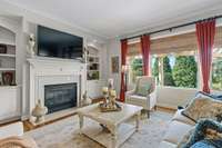 Formal Living Room with gas fireplace and built ins look out onto a beautifully manicured yard.