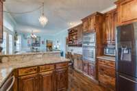 The beautiful chandelier suspended over the peninsula island, creates a focal point and adds elegance to the kitchen space.