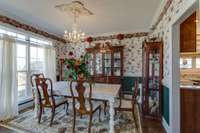 The formal dining room features a stunning chandelier that casts a warm glow over the room. The rich hardwood floors add an element of elegance, complementing the double windows that let in plenty of natural light.