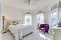 The third bedroom features plush carpeting, a built-in bookcase and large closet. The three arched windows create a bright and airy atmosphere that also add architectural interest to the room.