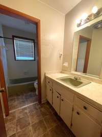 Full bathroom is divided, with tub and toilet area separate from the vanity area