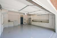 Garage with cabinet storage, full refrigerator and epoxy flooring