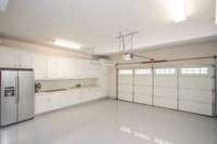 Garage with cabinet storage, full refrigerator and epoxy flooring