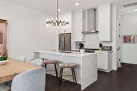 Additional counter seating at the kitchen's island is perfect for accommodating larger groups and for inviting more intimate conversation during meal preparation. The crisp, sleek lines of the space and bright white counters offer a light, airy feel.