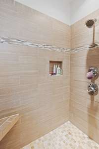 Tiled shower in primary bath with bench.