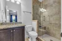 Media Room/6th Bedroom en-suite bath.  12x12 neutral tile on floor and shower surround.  Seamless shower door. Raised height vanity with granite countertop.