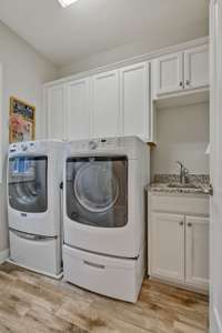 Laundry room has granite countertop raised height laundry sink.  Upper cabinet storage. 6x24 wood-look tile.  Magtag washer/dryer with pedestals REMAIN.