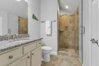 3rd floor full bath with walk-in shower w/seamless door,  neutral 12x12 tile on floor & shower surround.  White raised height vanity w/granite countertop. Access to walk-in attic storage behind bathroom door.