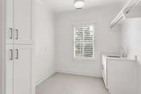 Laundry room equipped with a sink, tankless hot water heater, and additional storage space.