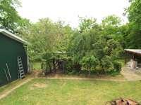 Back yard-lot continues behind garage-gazebo in this small grove of shade trees