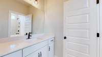 The private bathroom has abundant cabinets and a tub and shower combo with custom ceramic tile*