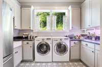 Luxurious laundry/utility room with decorative tile floor, double wide refrigerator, and lots of cabinets