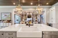 Farmhouse sink and white quartz counter grace the large kitchen island