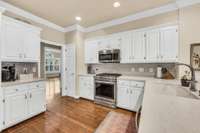 The kitchen features hardwood floors, quartz counters, stainless appliance, pantry and tile backspash.