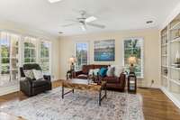 The light-filled sunroom features two walls of windows and a wall of bookshelves. This versatile space can be utilized for a variety of purposes. A walk-in laundry room adjoins this room.