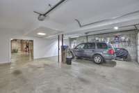 The oversized side-entry basement garage features garage door openers. Check out the additional space around the current SUV in the parking area. A double opening leads to the full unfinished area.