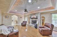 A tray ceiling mural evokes the tranquility of living in this peaceful setting. The living room showcases beautiful hardwood flooring and a stacked stone, fireplace, adding warmth and charm.