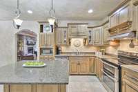 Let’s take another peek at this kitchen! This home is spotless! Notice the staggered custom cabinets and how the stacked stone fireplace is perfectly visible from the island.