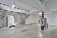 The stairs from the upper level lead down to the basement, which also features a pedestrian door for easy access to the sidewalk and driveway. Please note, the professional car wash vac in the photo will NOT remain.