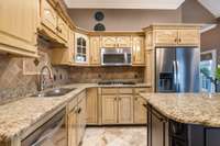 Stainless appliances and gas cooktop, travertine flooring.