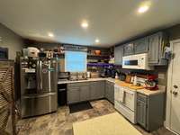 Updated kitchen with newer cabinets and open shelving. Stove and microwave remain, refrigerator does NOT remain.