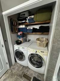 Laundry closet has open shelving for additional storage.