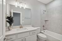 The ensuite bath space has a tub/shower combo, tile flooring and vanity with brushed nickel fixtures.