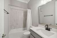 The ensuite bath features tile flooring and tile surround in the tub/shower combo and a framed mirror over the vanity.