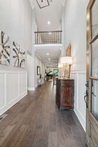 Other features of the foyer include a black metal chandelier, views from the catwalk above, judges paneling and crown molding.