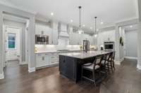 Continuing the elegance of this well appointed kitchen includes pendant lighting over the island, a butler’s pantry/appliance storage area and walk-in pantry with wood shelving.