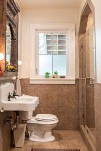 The downstairs full bath features a walk-in shower with frameless glass door and a window letting in sunlight while still providing privacy with the frosted glass elements.