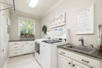 Doing laundry is less of a chore in this generously sized laundry room with utility sink and abundant cabinet space and a folding counter.