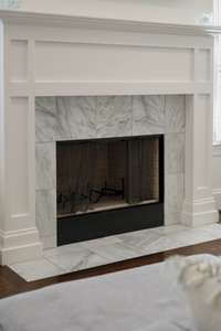 The fireplace is surrounded in lovely Carrara Marble tile keeping consistency of element choices within the design of the home.