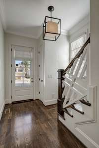 This photo is looking back towards the front door. Gorgeous millwork add a truly custom appeal to the staircase banister. 10' ceilings, unique modern lighting are only a few mentions of the lovely choices within the home.