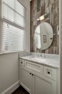 The half bath is located on the main level and features a freshly modern feel with its wood tiled focal wall at the vanity.