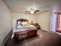 Basement Bedroom 12x14 carpet ceiling fan and drop ceiling leading into full bathroom